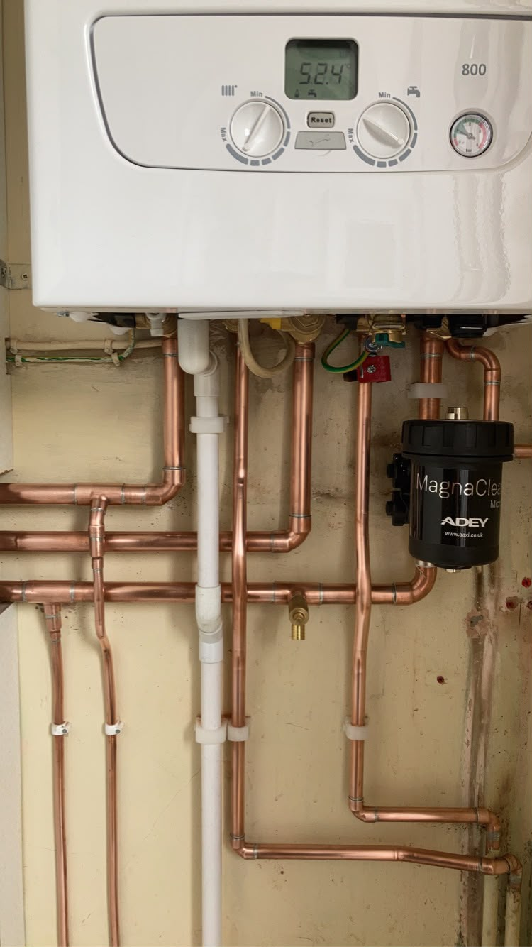 Neatly routed copper pipework beneath a boiler with a magnetic system filter